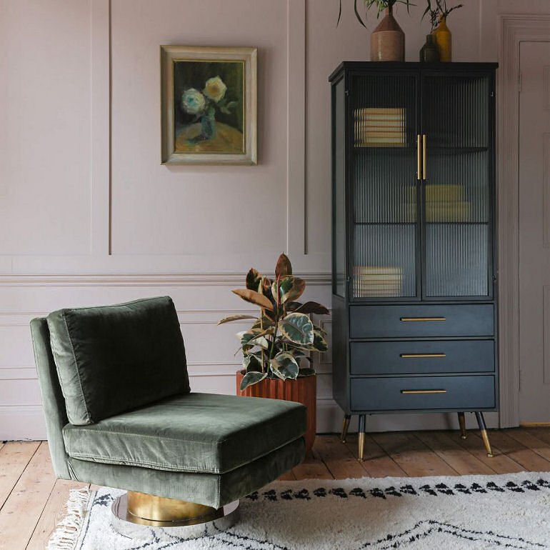 Graham & Green velvet armchair with swivel base next to tall blue Ike display cabinet