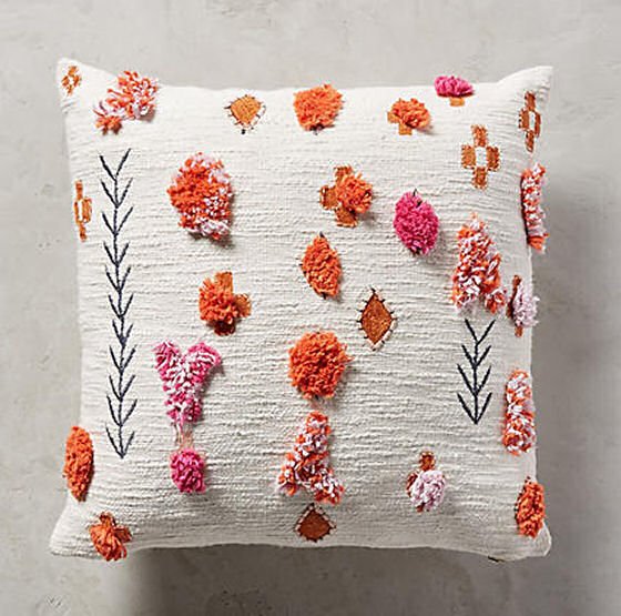 White Heradia cushion with orange and pink tufting and pompoms from Anthropologie
