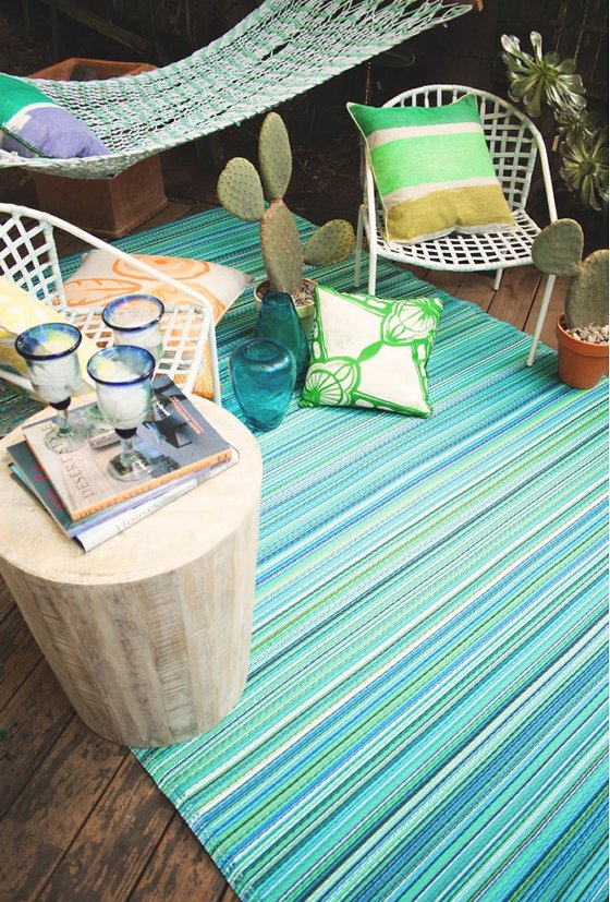colourful turquoise striped outdoor rug with hammock, chairs and cushions