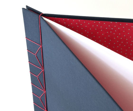 Detail of hardback A4 handbound journal with navy covers, red stab binding and red polka dot lining papers