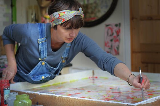 Woman wearing marbled silk scarf in hair working in her studio leaning over marbling tray