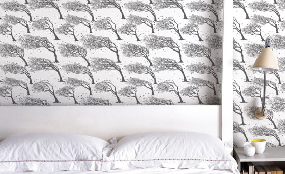 Modern wallpaper behind bed with dark grey trees on white background