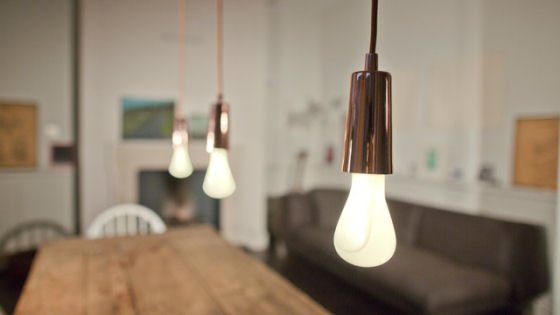 Plumen 002 light bulb with copper drop cap Plumen 002 light bulb with copper drop cap in room setting