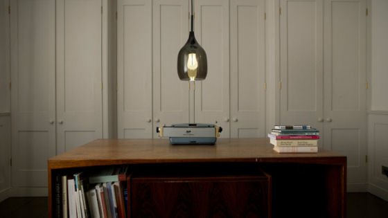 Plumen 002 light bulb in glass shade Plumen 002 light bulb in glass shade hung over desk