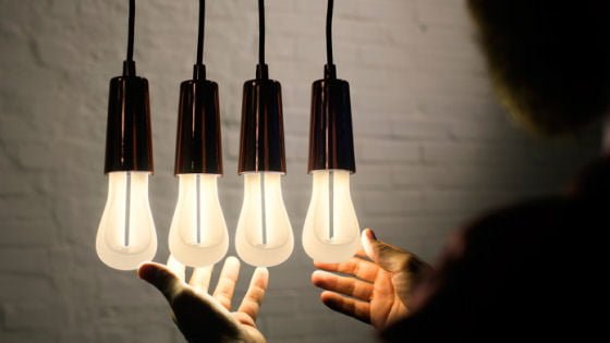 Plumen 002 light bulbs Four Plumen 002 light bulbs with metallic drop cap fittings and persons hands