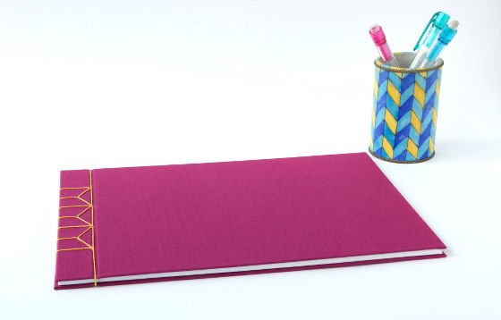Fuschia pink handmade journal with yellow linen stab binding and colourful pen pot