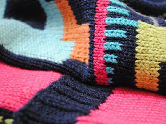 Navy, pink, turquoise and yellow knitted textile with geometric design