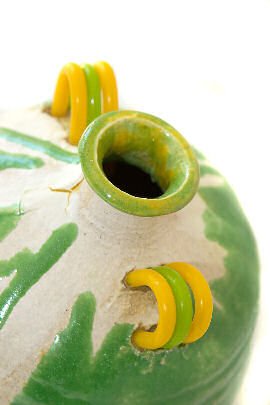 Detail of green and white modern ceramic vessel with yellow and green plastic handles